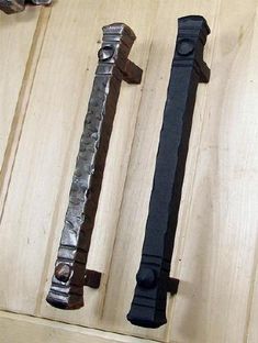 three different types of metal handles on a wooden cabinet door, one is black and the other is silver