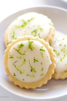 three cookies with white icing and green sprinkles are on a plate