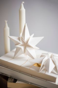 an origami star on top of a book with two candles in the background