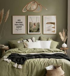 a bedroom with green walls and pictures on the wall above the bed, along with two wicker baskets