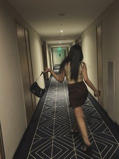 a woman is walking down the hallway with her handbag in her other hand,