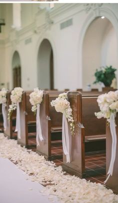 the aisle is lined with wooden pews decorated with white flowers and ribbon tied to them