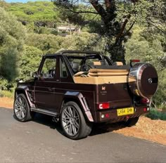 a brown truck parked on the side of a road next to a tree filled hillside