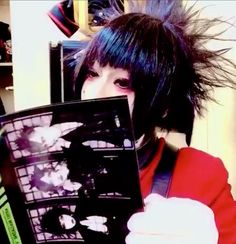 a person with black hair holding up an album