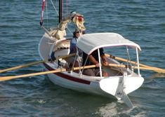 a man riding on the back of a white boat with two oars in the water