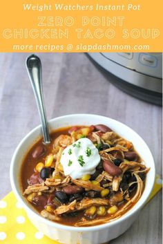 a white bowl filled with chicken taco soup and topped with sour cream on top