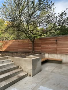 a concrete bench sitting next to a tree on top of a cement slab covered ground