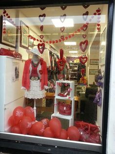 a store window with red and white balloons in the window, hearts strung across the windows