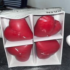 four red heart shaped candles in a box on a table next to a white ball