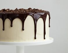 a cake with white frosting and chocolate drizzles on it's side