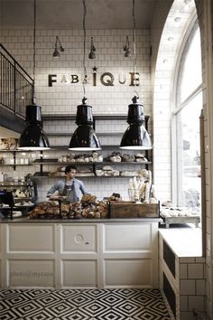 the interior of a restaurant with black and white tiles on the floor, counter tops, and hanging lights