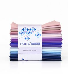 a stack of pure solid cottons in various colors and patterns on a white background