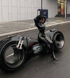 a woman dressed in black riding on the back of a motorcycle