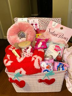 a basket filled with lots of baby items on top of a wooden table next to a stuffed animal