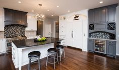 a large kitchen with an island in the middle and two bar stools next to it