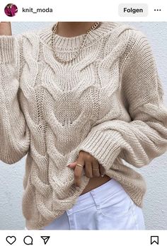 a woman wearing a sweater and white pants with her hand on her hip, posing for the camera