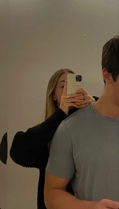 a man and woman taking a selfie in front of a mirror