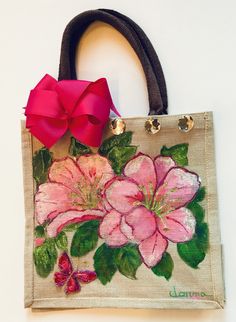 a handbag with flowers painted on it and a red bow hanging from the handle