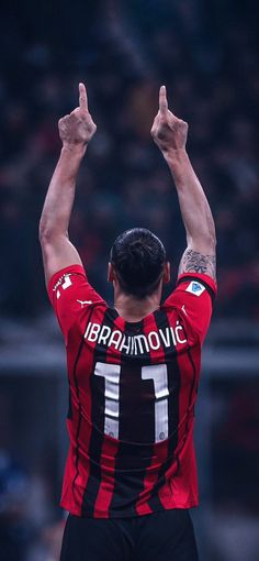 a soccer player raising his arms in the air with one hand up and two fingers raised