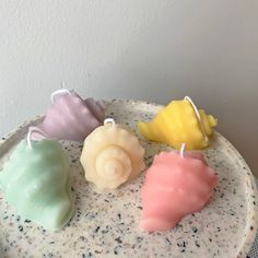 four small candles sitting on top of a white plate next to each other in different colors