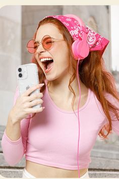 a woman wearing headphones and listening to music on her cell phone while standing in front of stairs