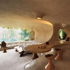 a living room filled with lots of furniture next to a large window covered in plants