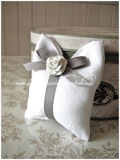 a white pillow with a flower on it sitting on a table next to a box