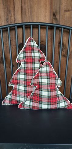 a plaid christmas tree pillow sitting on top of a black chair next to a wooden wall