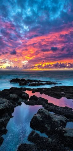 the sun is setting over some rocks and water