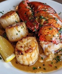 a white plate topped with lobster and scallops covered in gravy next to a lemon wedge