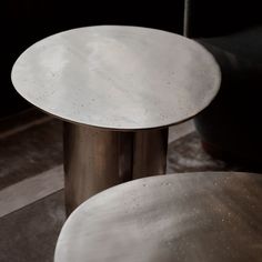 two white tables sitting next to each other on top of a carpeted floor in front of a black wall