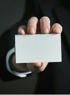 a person in a suit holding up a white business card with the words, what is it?