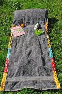 a blanket and some food on the ground in the grass with an orange, yellow and blue striped edge