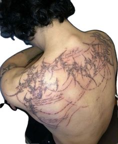 the back of a woman's shoulder with tattoos on it