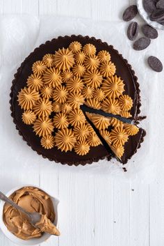 a pie with chocolate frosting and an oreo crust on top, next to a bowl of cookies