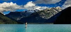 a person standing in the middle of a lake surrounded by mountains