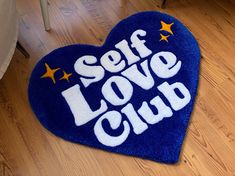 a blue heart shaped rug with the words self love club written in white on it