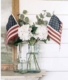 an american flag and flowers in a vase on a mantle next to a framed photograph