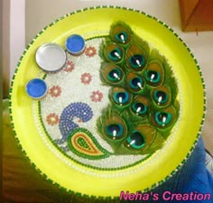 there is a yellow plate with peacocks on it and some blue buttons in the middle