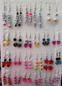 there are many different earrings hanging on the wall with name tags attached to each earring