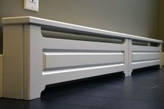 a white bench sitting on top of a hard wood floor next to a light switch