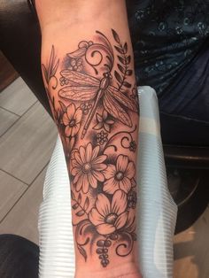 a woman's arm with flowers and a dragonfly tattoo on her left wrist