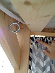 a person's hand is pointing at the curtain rod that hangs on the ceiling