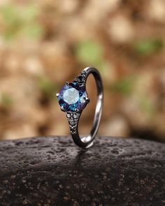 an engagement ring with a blue topazte surrounded by white diamonds on a rock