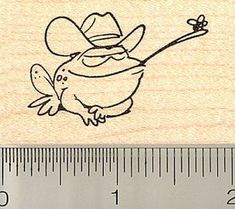 a rubber stamp with an image of a frog wearing a cowboy hat and holding a stick