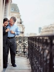 an older man and young woman standing on a balcony