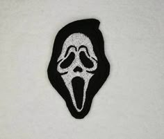 a black and white embroidered patch with a scream face on it's back side