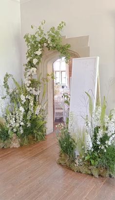 an image of a room decorated with flowers and greenery in front of a mirror