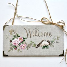 a welcome sign hanging on a wall with flowers and birds painted on the front side