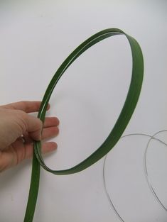 a hand holding a green ribbon on top of a white table